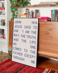 John 14:6 I Am the Way wall art leaning beside a wooden dresser with books and plants nearby