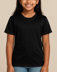 Young Indian girl wearing a black Badger 2120 Youth B-Core T-Shirt on a neutral beige studio background — moisture-wicking athletic blank ideal for custom printing by Lumiere Vive.