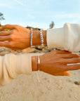 Seek Him string bracelet styled with additional bracelets on wrists at the beach