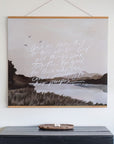 All Things Work Together scripture wall art featuring a muted landscape and white Romans 8:28 lettering, displayed with wooden banner rails above a dark cabinet.