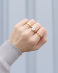 Jesus Fish Gold-Tone Ring styled with other rings on a hand extending from a gray sleeve