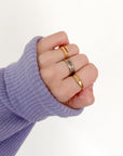 Cross Gemstone Gold-Tone Ring styled with other rings on a hand extending from a lavender sweater sleeve