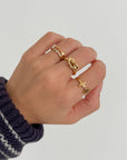 Stacked Cross Gem Gold-Tone Ring styled with other rings on a hand against a light background