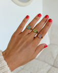 Lilac Enamel Cross Ring styled with other enamel cross rings and a cream knit sleeve indoors