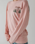 Person wearing a pink sweatshirt with a graphic design on a plain background