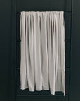 White curtain hanging on a black ladder against a dark wall
