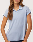 Woman wearing a light blue Adidas A690 Women’s Blend Polo on a neutral background — premium moisture-wicking performance polo designed for embroidery and custom branding by Lumiere Vive.