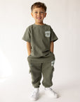 Child modeling hunter green Amen Club cargo sweatpants with a coordinating shirt