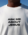 Close-up of bold black Ask Me About Jesus lettering on cream cotton tee