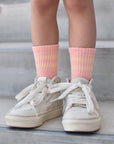 White sneakers and pink socks on a concrete surface