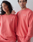 Two people wearing matching pink sweatshirts and pants with a brand logo.