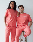 Two people wearing matching coral outfits with white sneakers against a plain background