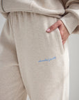 Close-up of Heather Eggshell sweatpants showing subtle blue embroidery near the hip.