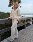 Woman wearing Heather Eggshell wide leg sweatpants beside a wooden boardwalk railing.