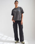 Model wearing the Lamp Black Believe in Miracles tee with black pants and green sneakers
