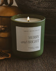 Lit Merry and Bright olive jar candle styled with warm-toned holiday decor.