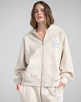 Front view of the Heather Eggshell full-zip hoodie with blue chest detail and front pockets