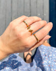 John 3:16 Gold-Tone Ring worn alongside other rings on a hand above blue floral fabric
