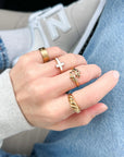 Hand wearing multiple gold rings with a blurred background