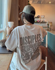Back view of the Chateau Grey Disciples Heavyweight Tee showing bold lettering and a detailed graphic inside a café