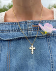 Close-up of white-detailed cross pendant on a gold-tone paperclip chain