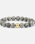 Gray beaded bracelet with a gold accent on a white background