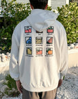 Person wearing a white hoodie with colorful symbols and text on the back, standing outdoors.