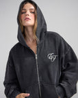 Close-up of the God of Miracles Full Zip Hoodie with the hood up and embroidered chest detail visible.