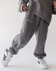 Angled view of Grey Mist God of Miracles sweatpants showing the oversized leg fit and elastic cuffs