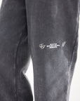 Close-up of light-colored embroidery on the black God of Miracles sweatpants.