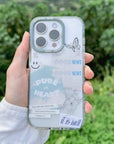 Person holding a phone with a clear case featuring text and graphics outdoors.