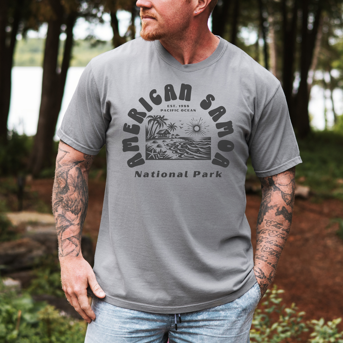 Man wearing a gray t-shirt with 'American Samoa National Park' graphic outdoors.