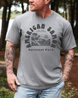 Man wearing a gray t-shirt with 'American Samoa National Park' graphic outdoors.