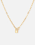 Gold-tone paperclip chain necklace with an open heart detail and a small padlock charm on a light background.