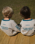Back view of two children wearing Heaven’s Favorite kids crewneck sweatshirts while seated outdoors