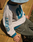 Close-up of teal Heaven’s Favorite sleeve lettering on a Pumice Stone kids sweatshirt