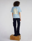 Full-length back view of the Holy Ghost Sterling Blue tee styled with dark pants