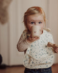 Child drinking from a mug with a neutral background