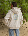 Model wearing the Nimbus Cloud Jesus Is Alive hoodie with pastel lettering and floral accents on the back