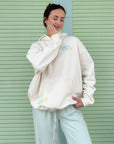 Model wearing the Nimbus Cloud Jesus Is Alive hoodie in front of a green shutter