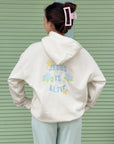 Model showing the Jesus Is Alive back design on a Nimbus Cloud hoodie in front of a green shutter