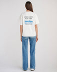 Full-length back view of a woman wearing the Jesus Loves New York tee with blue jeans.