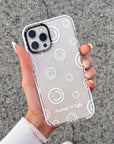 Clear phone case with smiley face pattern held by a person on a textured surface
