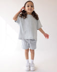 Child wearing the light blue Kingdom Club shorts with a coordinating T-shirt and white sneakers.