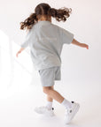 Child playing in the Kingdom Club Open Air Blue Kids Tee, showing its roomy fit