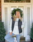 Woman wearing the Kingdom Culture long sleeve tee under a dark vest outside a front doorway.