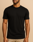 Male model wearing a black Lumiere Vive Everyday Tee on a neutral beige studio background — soft cotton everyday essential ideal for custom printing.