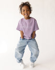 Child posing in the Quiet Violet Me Plus God Kids Tee with light-wash jeans