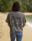 Back of grey heavyweight tee with oversized tonal Jesus Is King lettering, worn with jeans outdoors