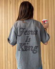 Back view of grey Jesus Is King appliqué tee worn indoors